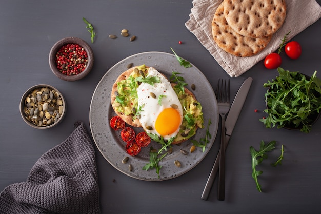 Breakfast avocado sandwich with fried egg and tomato