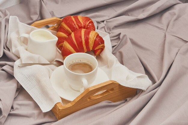 Breakfast in bed, coffee with cream, croissants in jam