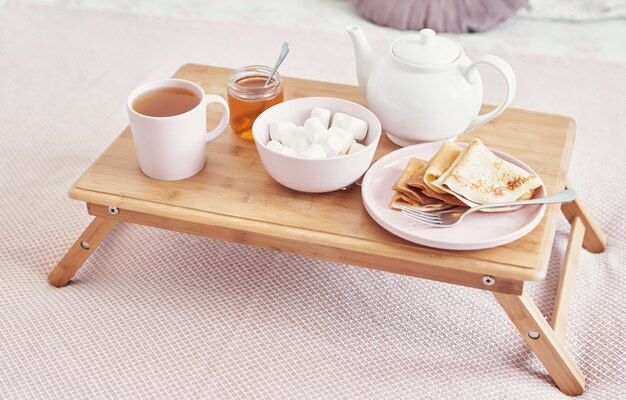 Breakfast in bed in hotel room. Accommodation. Breakfast in bed with tea cup with pancakes on tray