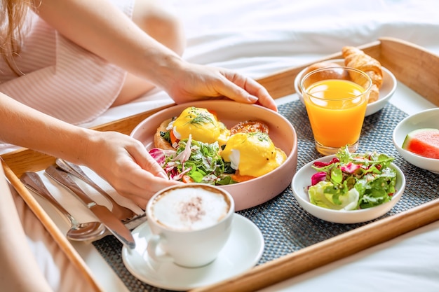 Breakfast in Bed with Coffee, Orange Juice, Salad, Fruits and Eggs Benedict