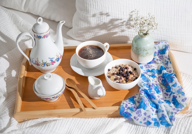 breakfast in bed on a wooden tray with a cup of coffee tea set and oatmeal