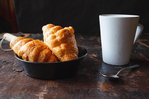 Breakfast bread, croissants and fresh milk on the wooden table.