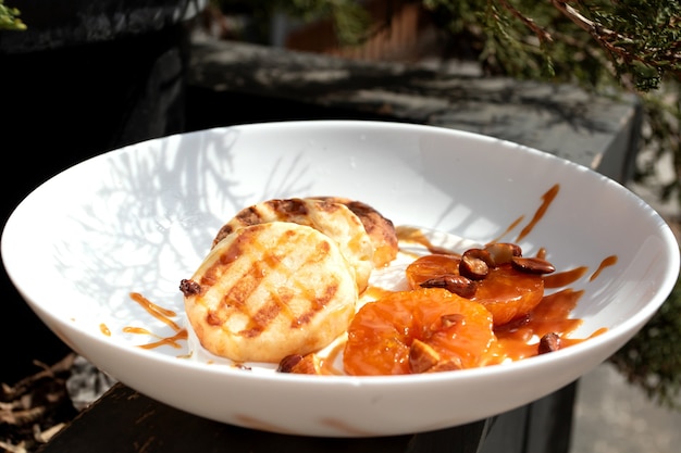 Breakfast in a cafe on the street during a pandemic. Cheesecakes with tangerines and caramel.