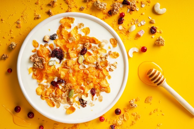 breakfast cereal cornflakes nuts seeds berries and honey in a bowl with milk