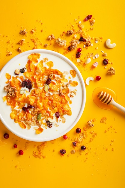 breakfast cereal cornflakes nuts seeds berries and honey in a bowl with milk