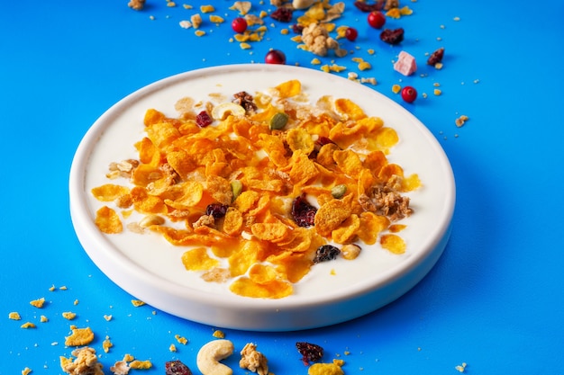 Breakfast cereal Cornflakes nuts seeds berries and honey in a bowl with milk