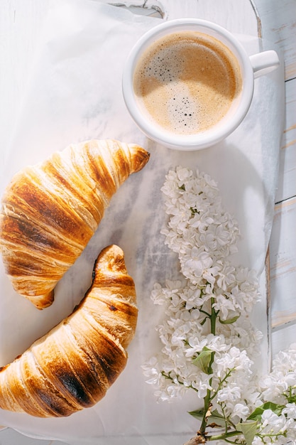 Breakfast concept hot and fresh croissant and a cup of coffee