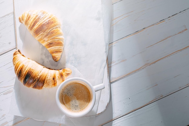 Breakfast concept hot and fresh croissant and a cup of coffee