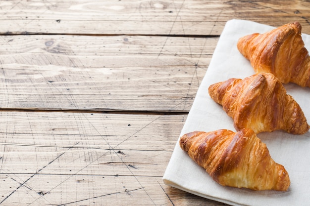 Breakfast croissants on a plate and a Cup of coffee, Wooden table.