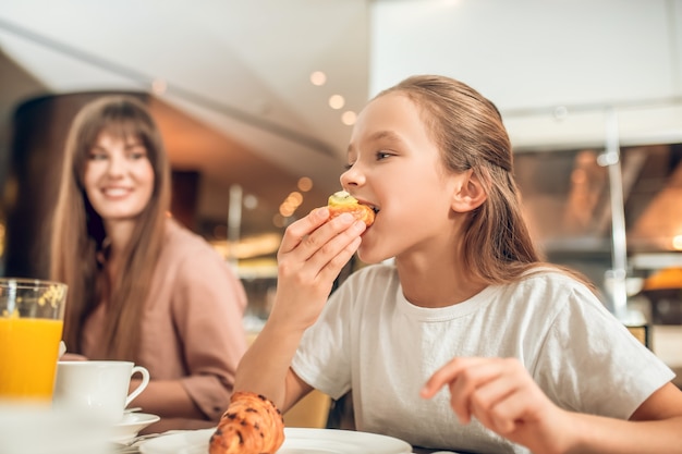 Breakfast. Cute girl biting a piece of sandwich