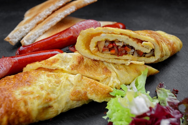 Breakfast fried omelet with vegetables fried sausages and toast