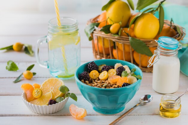 Breakfast of granola, fruit, freshly squeezed juice and tea on a white table.