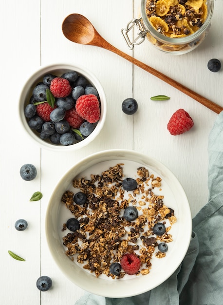 Breakfast granola with milk blueberry raspberry cornflakes top view wood background