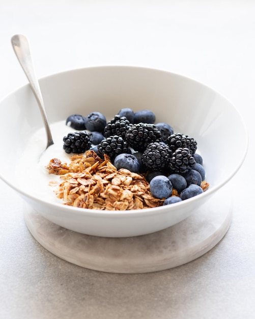 Breakfast granola with yogurt and berries on a concrete background