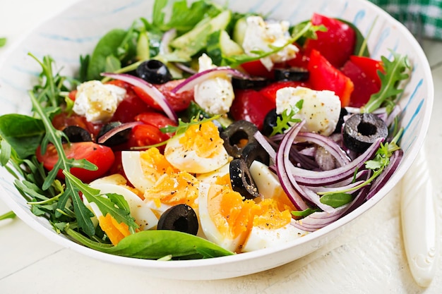 Breakfast Greek salad and boiled eggs Fresh vegetable salad with tomato cucumbers olives arugula and cream cheese Trendy food