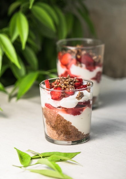 Photo breakfast layered parfait dessert with yogurt sponge biscuit and fresh strawberry white background copy space