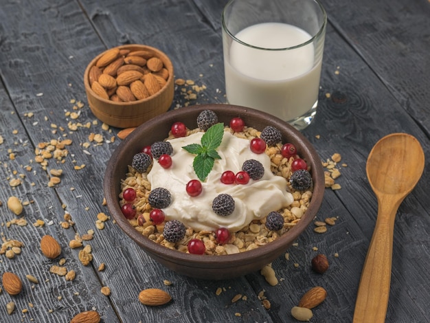 Breakfast of milk yogurt granola and berries on a wooden table