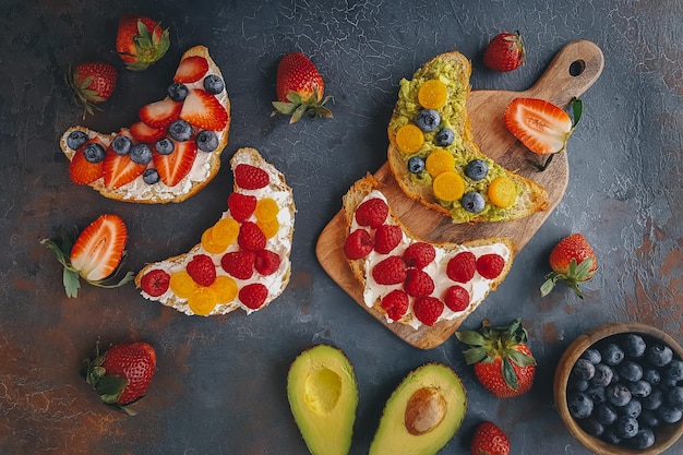 Breakfast, Mini pancakes with berries, croissants and avocado, Delicious summer food, Top view on a dark back