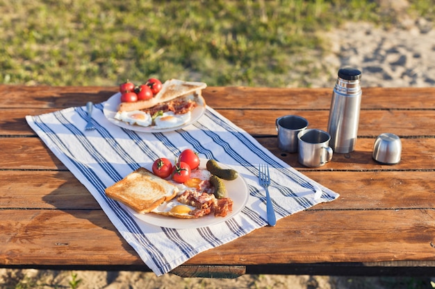 Breakfast in nature Fried eggs with bacon fried toast and hot coffee from a thermos