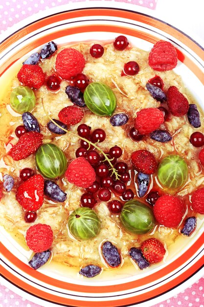 Breakfast oatmeal with berries and honey on white wooden background flat style top view overhead summer menu