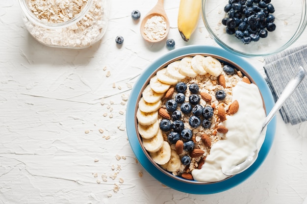 Breakfast, oatmeal with blueberry, banana almond and yogurt on a bowl in the morning.