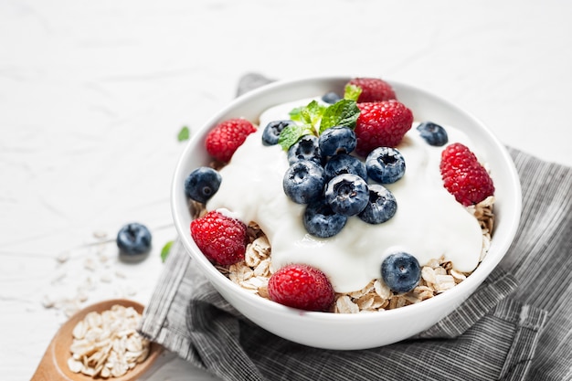 Breakfast, oatmeal with blueberry and raspberry on white bowl in the morning.