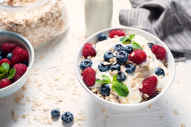 Breakfast, oatmeal with blueberry and raspberry on white bowl in the morning.