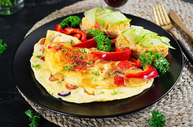 Breakfast. Omelette with paprika, cheese and tomatoes with sandwiches on black plate. Frittata - italian omelet.