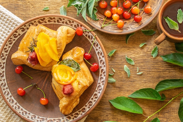 Breakfast in a rustic style in clay dishes croissants with cherries a cup of tea with mint top vi