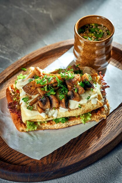 Breakfast sandwich with Omelette and mushrooms and white sauce Concrete background Hard light Vegetarian food Close up