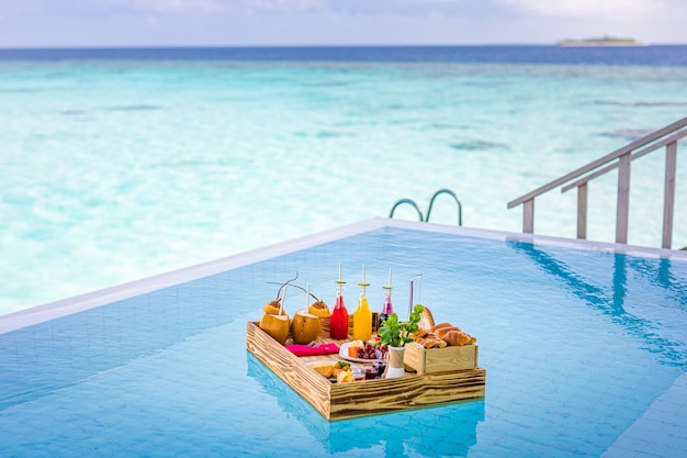 Breakfast in swimming pool, floating breakfast in tropical resort. Table relaxing in calm pool water