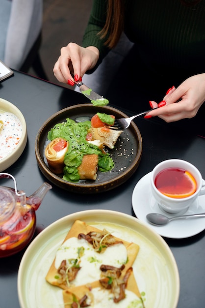 Breakfast table setting with pancakes, tea. Couple is eating