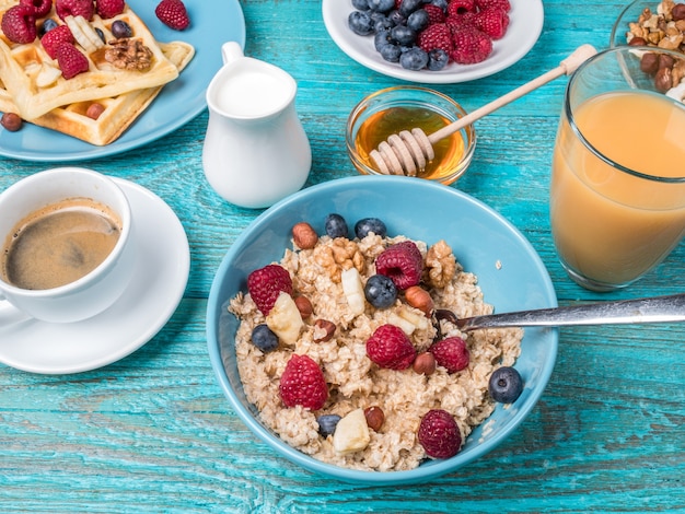 Breakfast table with waffles, oatmeal, cereals, coffee, juice and fresh berries