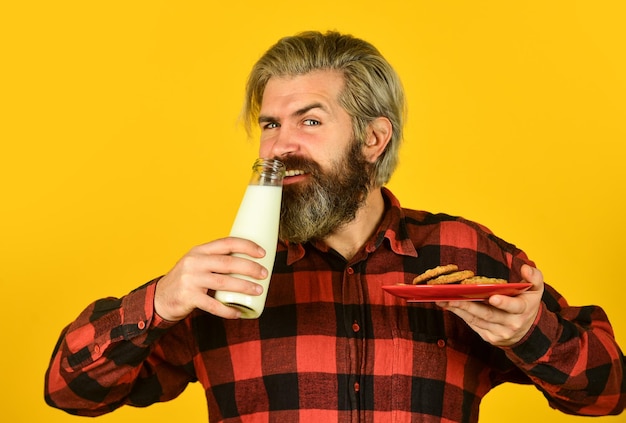 Breakfast tradition Happy hipster eat cookie dessert Milk and sweet cookie Delicious as in childhood Mature bearded man drink milk with cookie Yummy combination Recipe homemade cookies