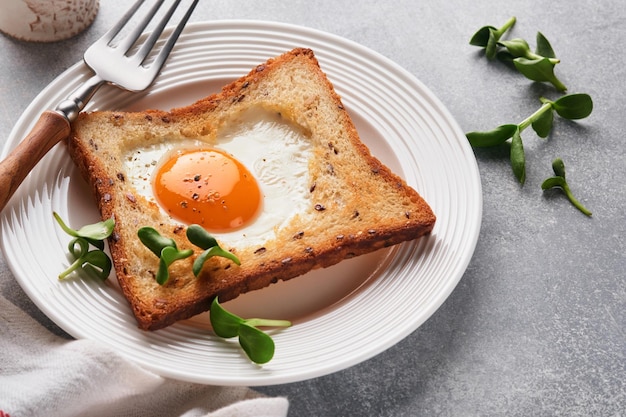 Breakfast on Valentines Day Heart shaped egg with toast and microgreens on light grey background breakfast table top Valentines day breakfast Top view Mock up