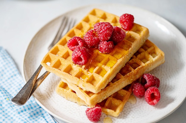 Breakfast waffles with berries in plate served with cup of tea