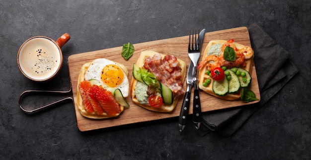 Breakfast waffles with fried eggs salmon cucumber and prawns