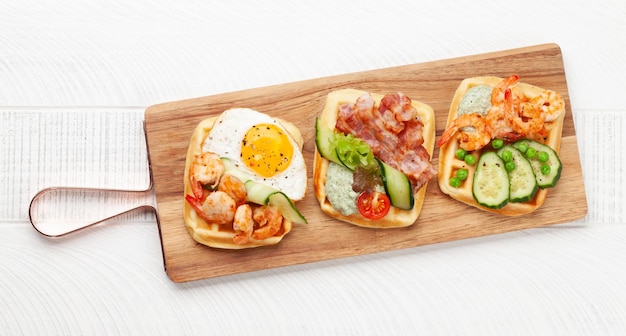 Breakfast waffles with fried eggs salmon cucumber and prawns