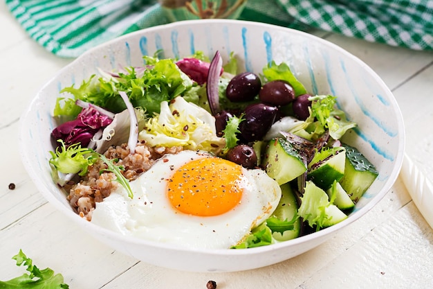 Breakfast wheat porridge with roasted egg cucumber and olives Healthy balanced food