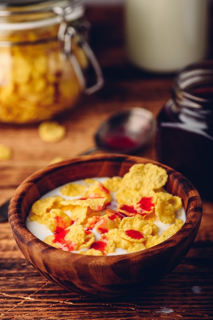 Breakfast with corn flakes milk and berry syrup