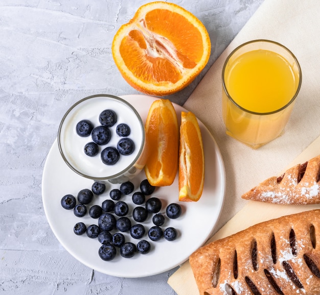 Breakfast with juice, oranges, buns and blueberries on concrete