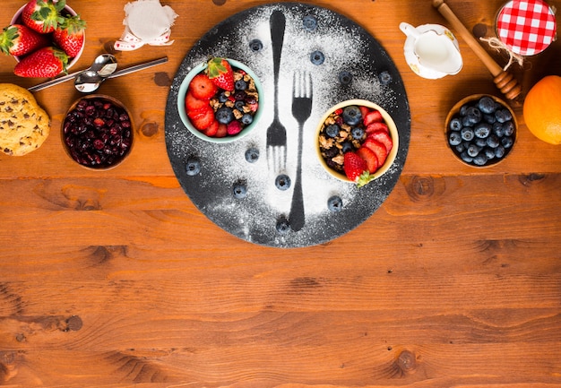 Breakfast with muesli and fresh fruits in bowls on a rustic wooden table