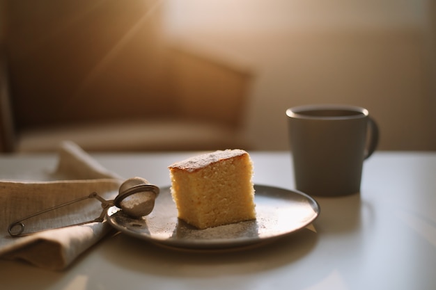 Breakfast with a piece of homemade cake on a plate and cup of coffee