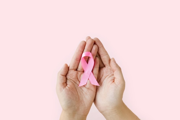 Breast Cancer Awareness Month Woman hands holding pink ribbon on pink background