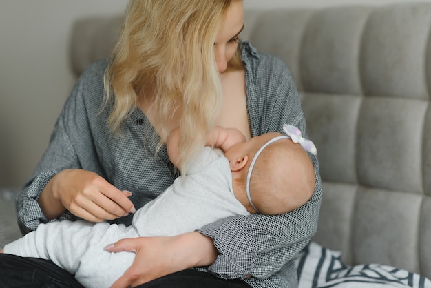 Breastfeeding Concept. Beautiful young woman lactating her toddler baby on couch at home, copy space