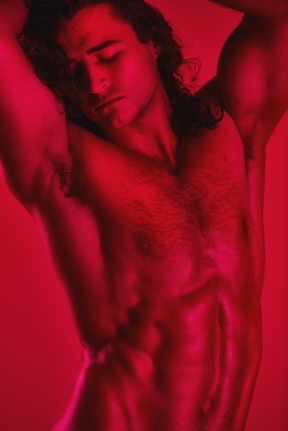 Breathtaking muscles Studio shot of a muscular young man posing shirtless against a red background