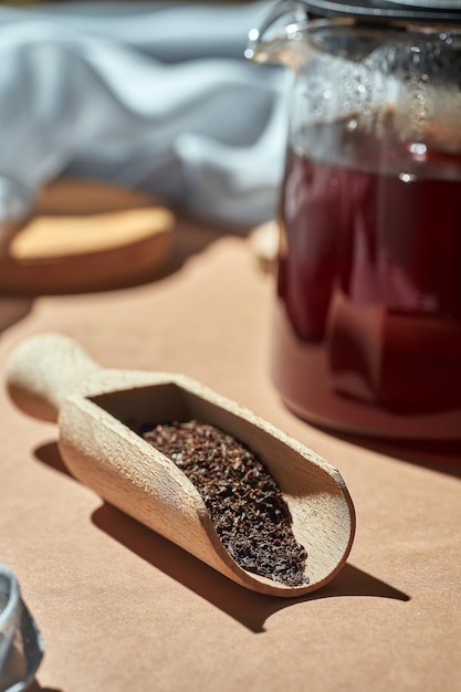 Brewed tea in a glass teapot on a brown background. Turkish tea in a wooden spoon