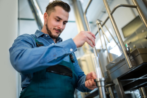 Brewer checking beer with hydrometer