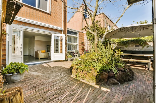 a brick patio with an umbrella and potted planter in the middle part of the yard surrounded by trees