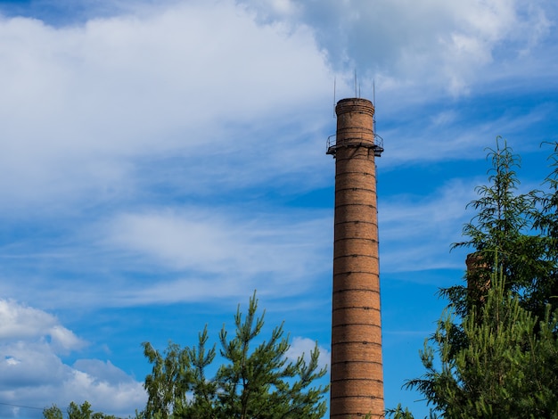 Brick pipe from the plant. The brick chimney rises to the sky. Old factory in the city.